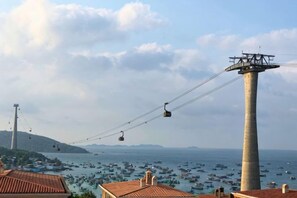 Un sistema de teleférico, una torre alta y una zona costera con barcos.
