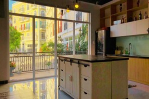A kitchen with a large window, a balcony, and a view of buildings. - Moonlight Hotel Phu Quoc (Phu Quoc Island)