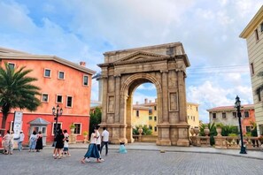 Un arco de piedra histórico en una plaza pública, flanqueado por edificios.