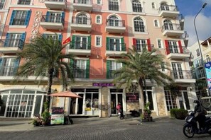 A multi-story hotel with balconies, palm trees, and a storefront. - Moonlight Hotel Phu Quoc (Phu Quoc Island)