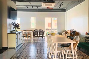 A dining area with a long table and chairs, a kitchen area with cabinets and a sink, and a patterned floor. - Moonlight Hotel Phu Quoc (Phu Quoc Island)