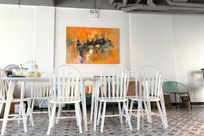 A dining area with a table and chairs, a painting on the wall, and a patterned floor. - Moonlight Hotel Phu Quoc (Phu Quoc Island)