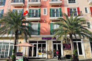 A multi-story building with balconies, palm trees, and storefronts. - Moonlight Hotel Phu Quoc (Phu Quoc Island)