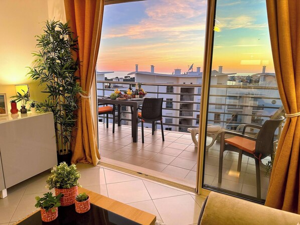 Ein Balkon mit Esstisch, Stühlen und einem Blumentopf.