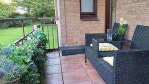 Un patio con un sofá de mimbre, una mesita y una planta en maceta.