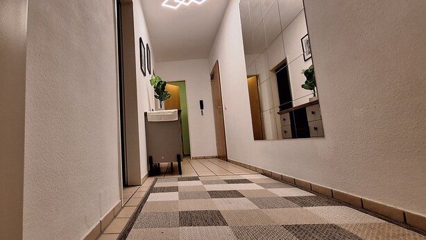 Un pasillo con piso a cuadros, un lavamanos y una puerta que da a una habitación.