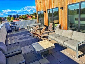 A rooftop patio with outdoor furniture, including a sofa, chairs, and a coffee table.