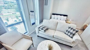 A modern living room with a sofa, armchair, and round coffee table.