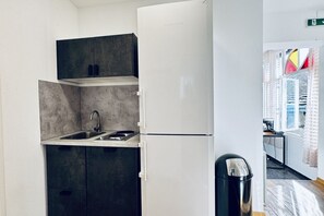 Une cuisine compacte dotée d’un évier encastré, d’un petit plan de travail et d’un réfrigérateur blanc.