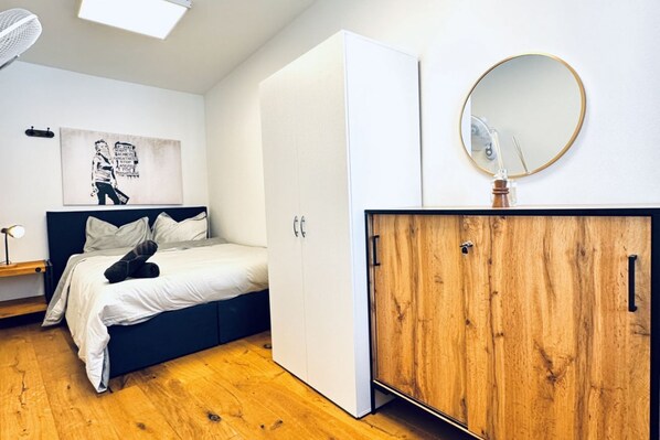Une chambre à coucher comprenant un lit, une armoire, un miroir et une œuvre d’art murale.
