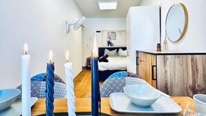 Een moderne kamer met een bed, een eettafel met kaarsen, een spiegel en een houten kast.