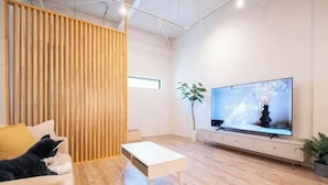 Un salon moderne avec un canapé, une table basse, un téléviseur et une cloison en bois.