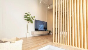 Un salon moderne avec un téléviseur, une plante en pot et un plancher en bois.