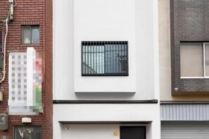 A modern building with a white facade, a black-framed window, and a door with a small circular window. - REPOS tsuruhashi-3 bedrooms, up to 8 people, 6 minutes walk to Tsuruhashi Station (Osaka)