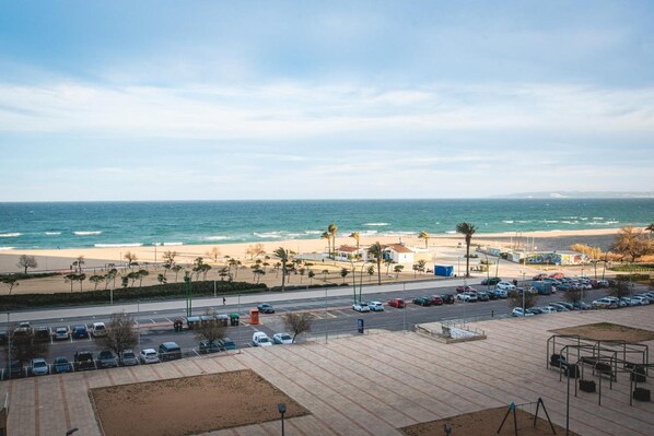 A coastal view with a beach, parking area, and a road leading to the beach.