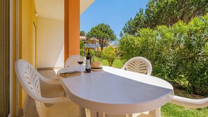 A white outdoor table with chairs, a bottle of wine, and a hat on it.