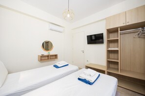 A hotel room with two beds, a TV, a wardrobe, and a mirror.