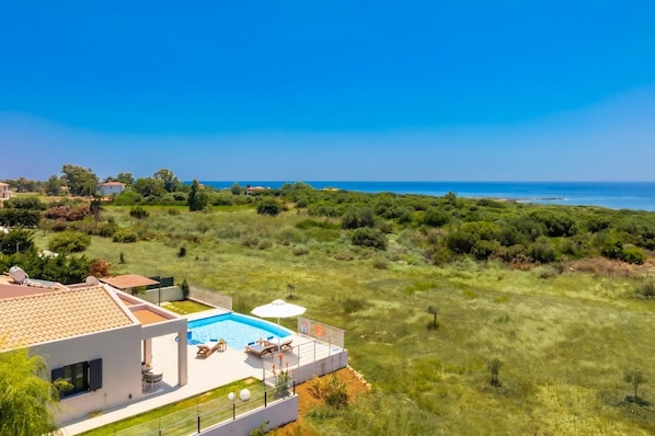 A residential property with a swimming pool, outdoor seating, and a view of the sea.