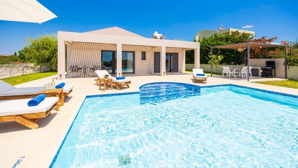 A modern outdoor swimming pool area with lounge chairs and a covered seating area. - Villa Pinelopi Tria - Two Bedroom Villa, Sleeps 5 (Ionian Islands)