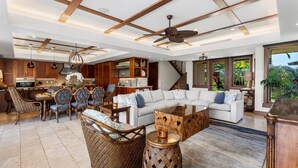 A spacious living area with a white sofa, wicker chairs, a coffee table, and a dining set. - Laule‘a #13 by Gather – Mauna Lani 4BR Villa w/ Golf Frontage, Private Pool/Spa (Kamuela)
