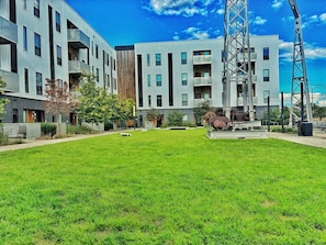 A modern building with multiple floors, balconies, and a central courtyard with grass.
