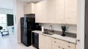 Eine moderne Küche mit hellen Holzschränken, einem schwarzen Kühlschrank und einem Geschirrspüler.