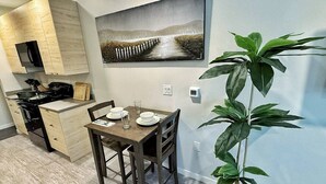 A compact kitchen with a dining area, a painting on the wall, and a potted plant. - Modern East Village Studio | Stylish Comfort near Dining & Shops (Des Moines)
