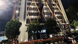 A tall, modern building with a distinctive geometric facade and illuminated windows at night.