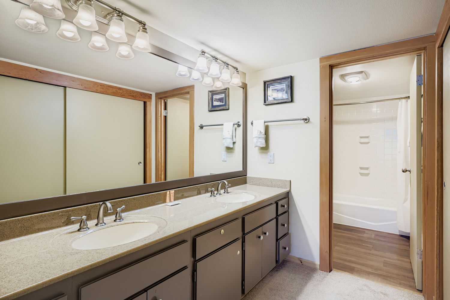 Une salle de bain avec un meuble-lavabo à deux vasques, un grand miroir et un espace douche.