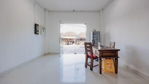A spacious room with a large window, a wooden desk, a chair, and a small stool. - RedDoorz near Ubud Village (Bali)