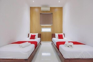 A hotel room with two beds, a wooden panel wall, an air conditioning unit, and a window. - RedDoorz near Ubud Village (Bali)