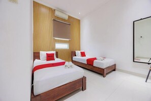 A hotel room with two beds, a wooden panel wall, a large mirror, and a white tiled floor. - RedDoorz near Ubud Village (Bali)