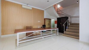 A spacious room with a wooden panel wall, a long table, and a staircase leading to an upper level. - RedDoorz near Ubud Village (Bali)