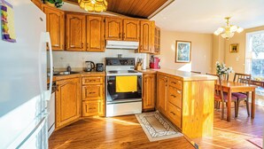 Una cocina con armarios de madera, una estufa y un comedor con mesa y sillas.