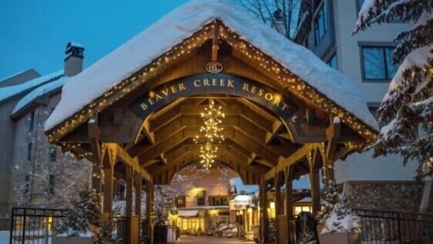 Entrada do Resort Beaver Creek, com galeria coberta, árvores cobertas de neve e uma placa sobre a entrada.