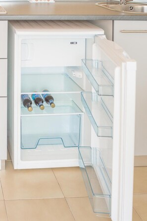 A refrigerator with clear shelves, a handle, and a control panel.