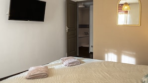 A bedroom with a bed, a television, a mirror, and a door leading to a bathroom. - Apartment 'La Glycine' with Wi-Fi and Air Conditioning (Montolieu)