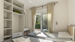 Un dormitorio con dos camas, un armario, un escritorio y una ventana con cortinas.