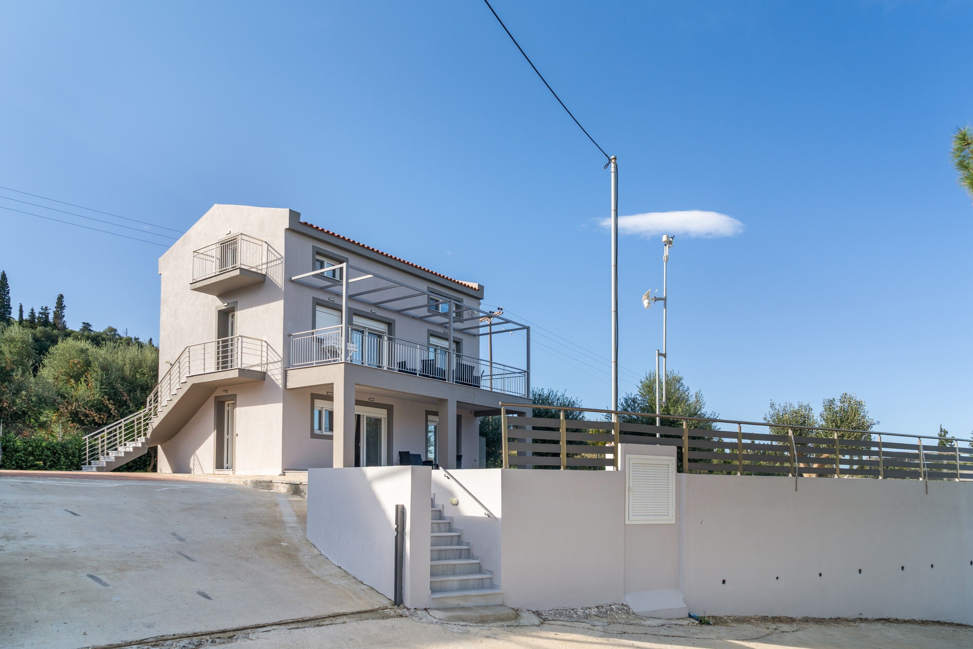 Un edificio moderno de dos pisos con balcón, escalera y fachada blanca.