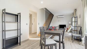 A modern dining area with a wooden table, chairs, and a black metal shelf unit.