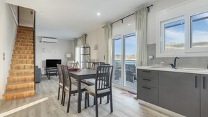 Una cocina moderna con comedor, una escalera y vistas al exterior.