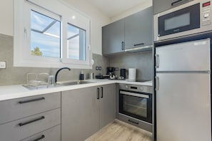 Een moderne keuken met grijze kastjes, een ingebouwde oven, een magnetron en een koelkast.