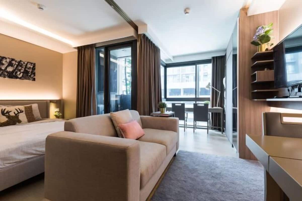 Een moderne hotelkamer met een bank, een bed, een bureau en een televisie.