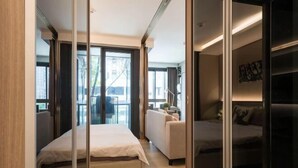 Une chambre d’hôtel moderne avec un grand lit, un canapé et une cloison en verre.