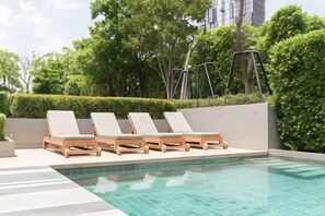 Une piscine avec des chaises longues et un jardin aménagé.