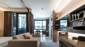Une chambre d’hôtel moderne équipée d’un canapé, d’une table à manger et d’un téléviseur.