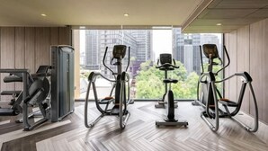 Une salle de sport moderne équipée de matériel d’exercice, dotée de grandes fenêtres et offrant une vue sur la ville.