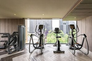 Un gimnasio moderno con equipo de ejercicio, ventanas amplias y vistas a la ciudad.