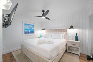 A bedroom with a bed, a ceiling fan, a nightstand, a lamp, and a framed picture on the wall. - Captiva Beachfront Front Condo| Heated Pool| Golf Cart (Captiva Island)