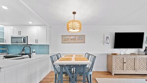 Een moderne keuken met witte kastjes, een blauwe eettafel en een hangende lamp.